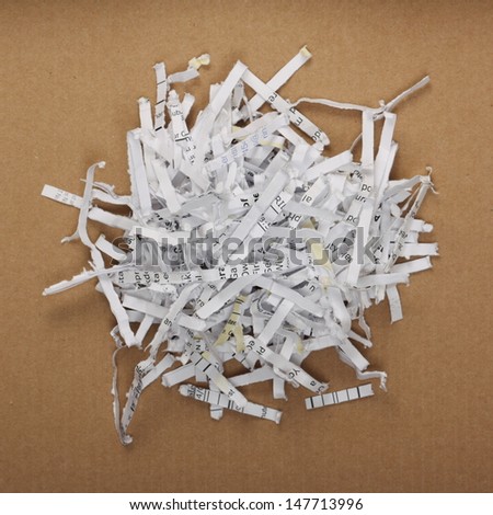 Strimmed or shredded paper piled on a cardboard background. We shred our bills and paperwork for recycling,to avoid identity theft and the copying of top secret documents
