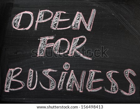 The phrase Open For Business hand written on a used blackboard.