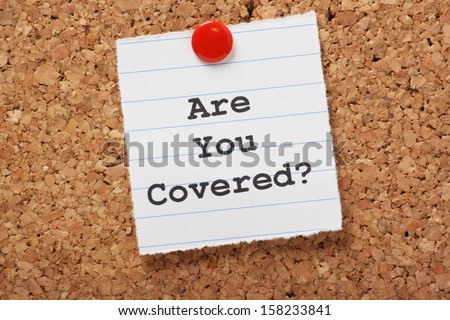 The words Are You Covered? typed on a scrap of lined paper and pinned to a cork notice board. Asking the question, are you insured for your car, travel, home or other liability.