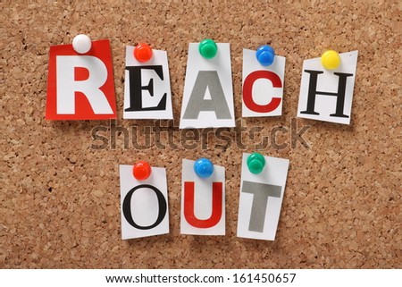 The phrase Reach Out in cut out magazine letters pinned to a cork notice board. We reach out to colleagues at work for assistance and to organizations and communities for help and support.