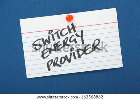 A reminder to Switch Energy Provider written on a note card pinned to a blue notice board. As power and energy providers increase their prices it pays customers to shop around for lower tariffs.
