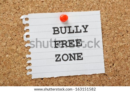 The words Bully Free Zone typed on a scrap of lined paper and pinned to a cork notice board. A concept for respect and tolerance in school and at work or home.