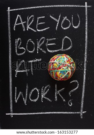 Are You Bored at Work? hand written in chalk on a blackboard next to a rubber band ball. A concept for job satisfaction or career change.