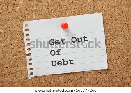 Get Out Of Debt Typed On A Piece Of Lined Paper Pinned To A Cork Notice Board. An Aspiration For Many In These Times Of Austerity And Rising Costs.