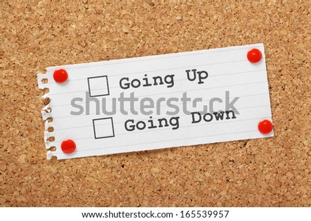 Tick Boxes next to the phrases Going Up or Going Down on a piece of paper pinned to a cork notice board, perhaps as a measure of popularity or success