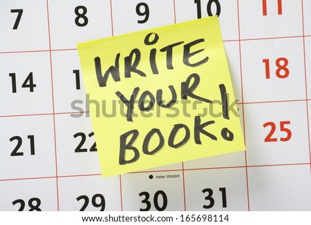 The phrase Write Your Book written on a yellow sticky paper note and stuck to a wall calendar as a reminder to get on with the work of starting your novel or other written work.