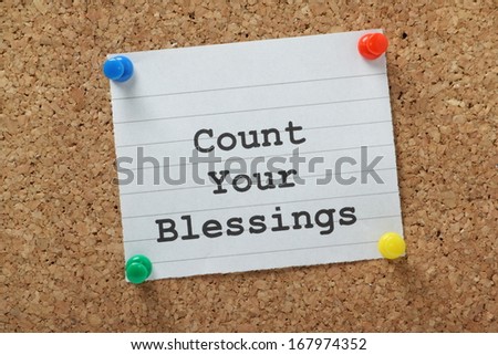 The phrase Count Your Blessings typed on a piece of lined paper and pinned to a cork notice board