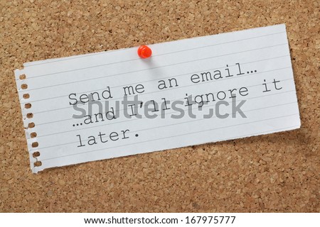 The phrase Send me an email and I\'ll Ignore it Later on a cork notice board. A concept for time wasting or avoiding being overwhelmed by communications and workload