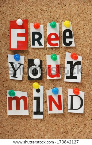 The phrase Free Your Mind in cut out magazine letters pinned to a cork notice board.
