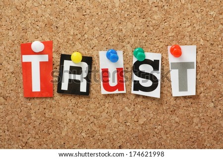 The word Trust in cut out magazine letters pinned to a cork notice board