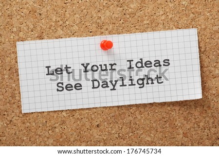 The phrase Let Your Ideas See Daylight typed on a piece of graph paper and pinned to a cork notice board