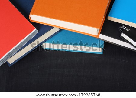 A pile of school textbooks or hardback books on a blackboard with copy space for your text