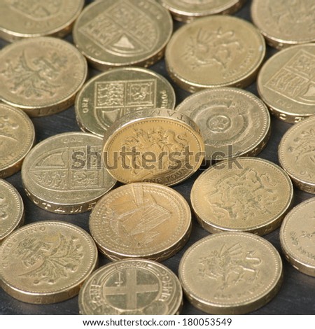 British Pound Coins on a black slate background with focus on the coin standing on edge in the middle