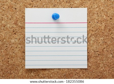 A blank lined note card pinned to a cork notice board with copy space