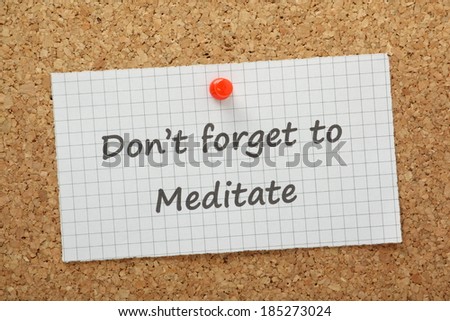 A reminder Don' Forget to Meditate typed on a piece of graph paper and pinned to a cork notice board