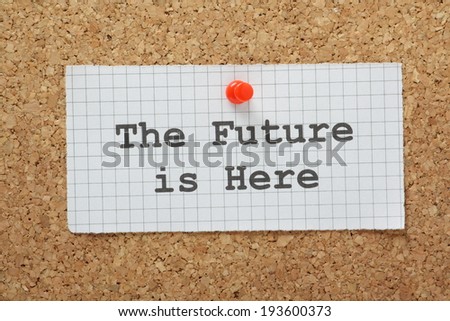 The phrase The Future Is Here typed on a piece of graph paper and pinned to a cork notice board
