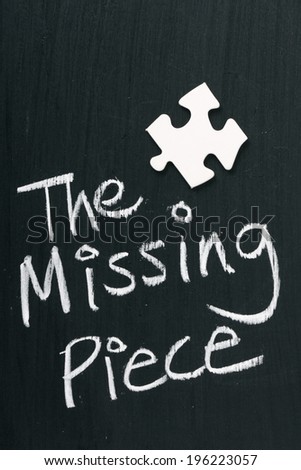 Single blank white jigsaw piece on a blackboard next to text saying The Missing Piece