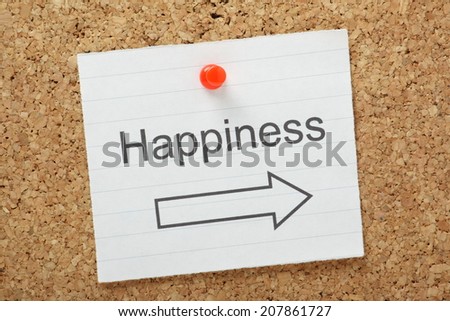 The word Happiness with an arrow pointing in the right direction on a paper note pinned to a cork notice board