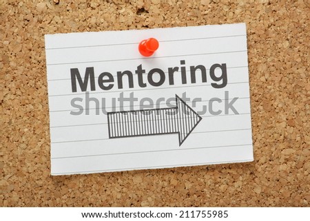 The word Mentoring typed on a piece of paper with an arrow pointing in the right direction, pinned to a cork notice board