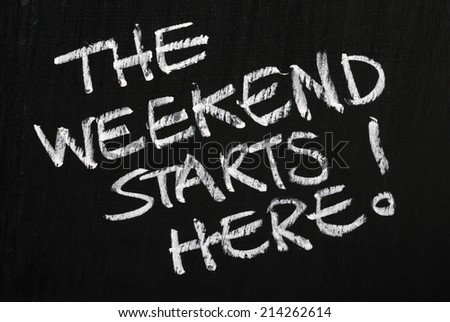 The phrase The Weekend Starts Here! written in white chalk on a used blackboard