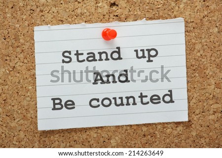 The phrase Stand Up and Be Counted typed on a piece of land paper and pinned to a cork notice board as a reminder
