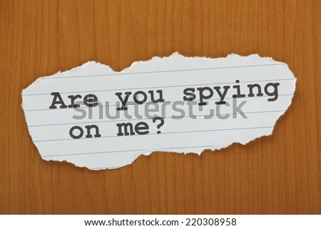 The question Are you spying on me? typed on a scrap of torn paper and left on wood effect background