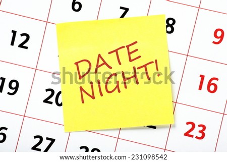 The phrase Date Night on a yellow sticky note attached to a calendar as a reminder of a special event