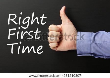 The phrase Right First Time on a blackboard with a male hand in a business shirt giving the thumbs up sign. Right First Time is a term used in Quality Control Improvement