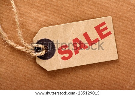 Sale announcement message in red text on a brown paper price tag and wrapping paper with string
