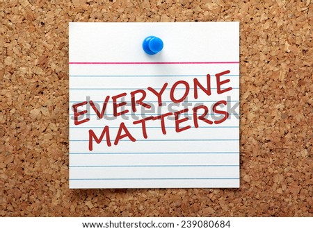 The phrase Everyone Matters in red ink on a lined index card pinned to a cork notice board