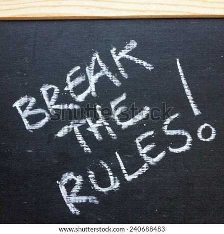 The phrase Break The Rules written by hand on a slate blackboard using white chalk