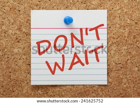 The phrase Don\'t Wait in red ink on a square index card pinned to a cork notice board as a reminder