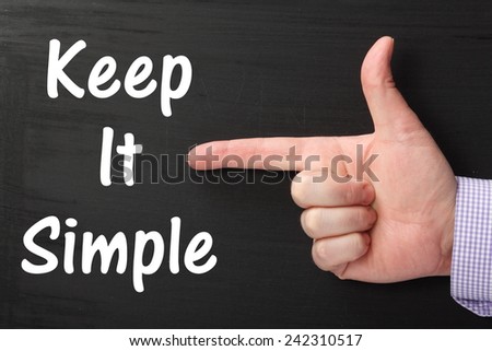 Male hand wearing a business shirt pointing an index finger at the phrase Keep It Simple written on a blackboard