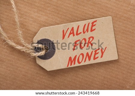 The phrase Value For Money printed on a paper price or luggage tag on a brown wrapping paper background with string