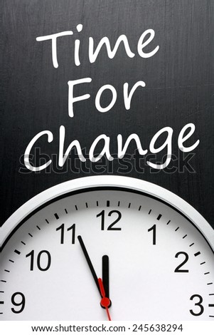 The phrase Time For Change written on a blackboard above a modern clock with the time at almost midnight or high noon