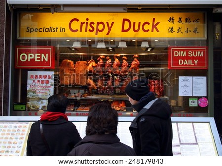 London, England - January 24, 2015: Three people at the menu board of a restaurant specializing in Crispy Duck in Chinatown, London. There are more than eighty restaurants in the Chinatown District.