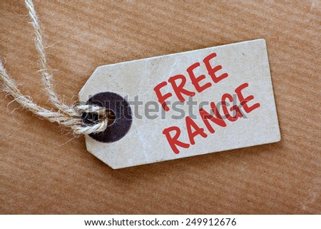 The phrase Free Range on a brown paper price or luggage tag with string on a brown wrapping or parcel paper background