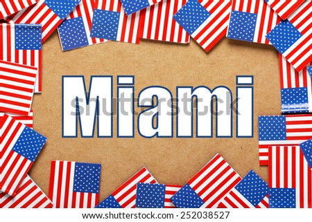 Miniature flags of the United States of America form a border on brown card around the name of the city of Miami