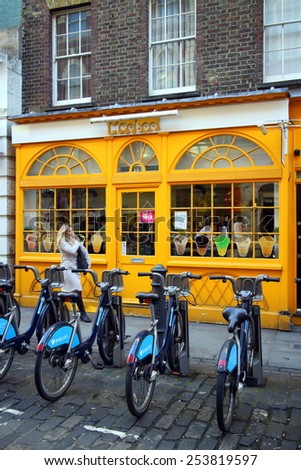 London, England - February 17, 2015: A pedestrian walks by Barclays Bank bicycles in front of a colorful cafe in London, England. The rental scheme provides over 5000 bikes for hire across the city.