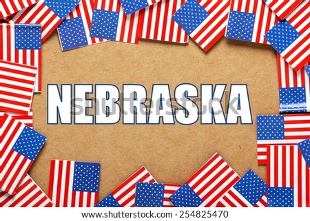 Miniature flags of the United States of America form a border on brown card around the name of the state of Nebraska