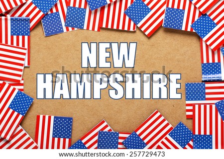 Miniature flags of the United States of America form a border on brown card around the name of the state of New Hampshire