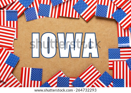 Miniature flags of the United States of America form a border on brown card around the name of the state of IOWA