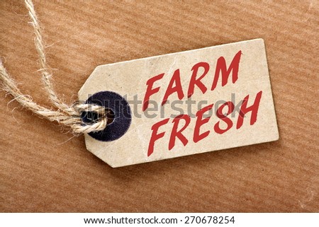 The phrase Farm Fresh on a paper price or luggage tag with string on a brown wrapping paper background