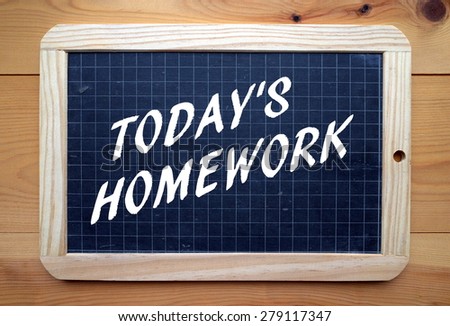The phrase Today\'s Homework in white text on a slate blackboard placed on a wooden surface