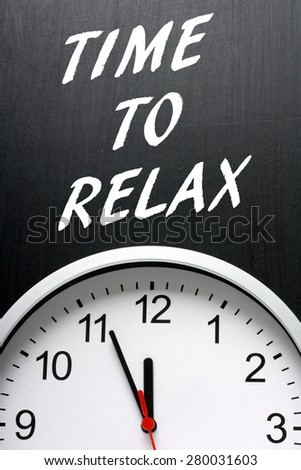 The phrase Time To Relax in white text on a blackboard next to a modern wall clock