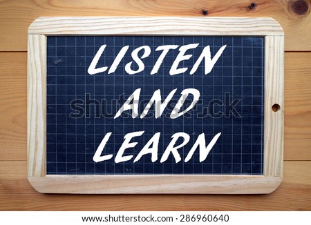 The phrase Listen and Learn in white text on a slate blackboard