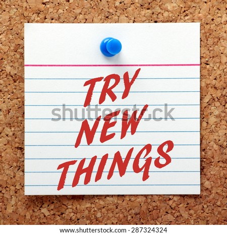 The phrase Try New Things in Red text on an index card pinned to a cork notice board as a reminder