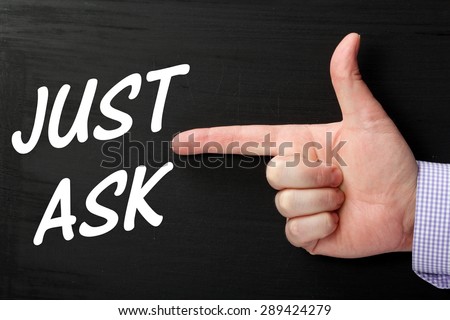 Male hand wearing a business shirt pointing a finger at the phrase Just Ask in white text on a blackboard