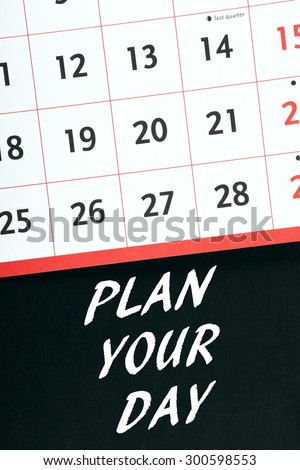 The phrase Plan Your Day in white text on a blackboard next to the page of a calendar or planner