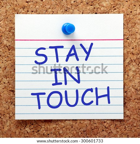 The phrase Stay in Touch in blue text on an index card pinned to a cork notice board as a reminder